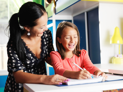 mother helping happy daughter with homework