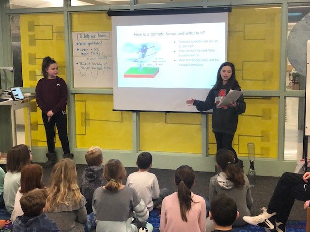 two students presenting to younger students