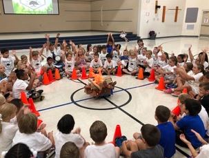 students in the gym sitting around pretend campfire