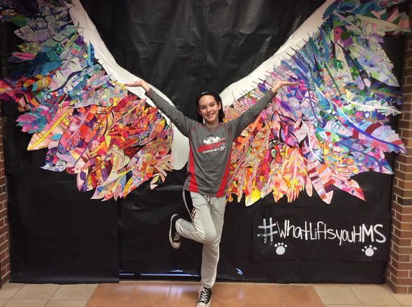 student in front of wings smiling